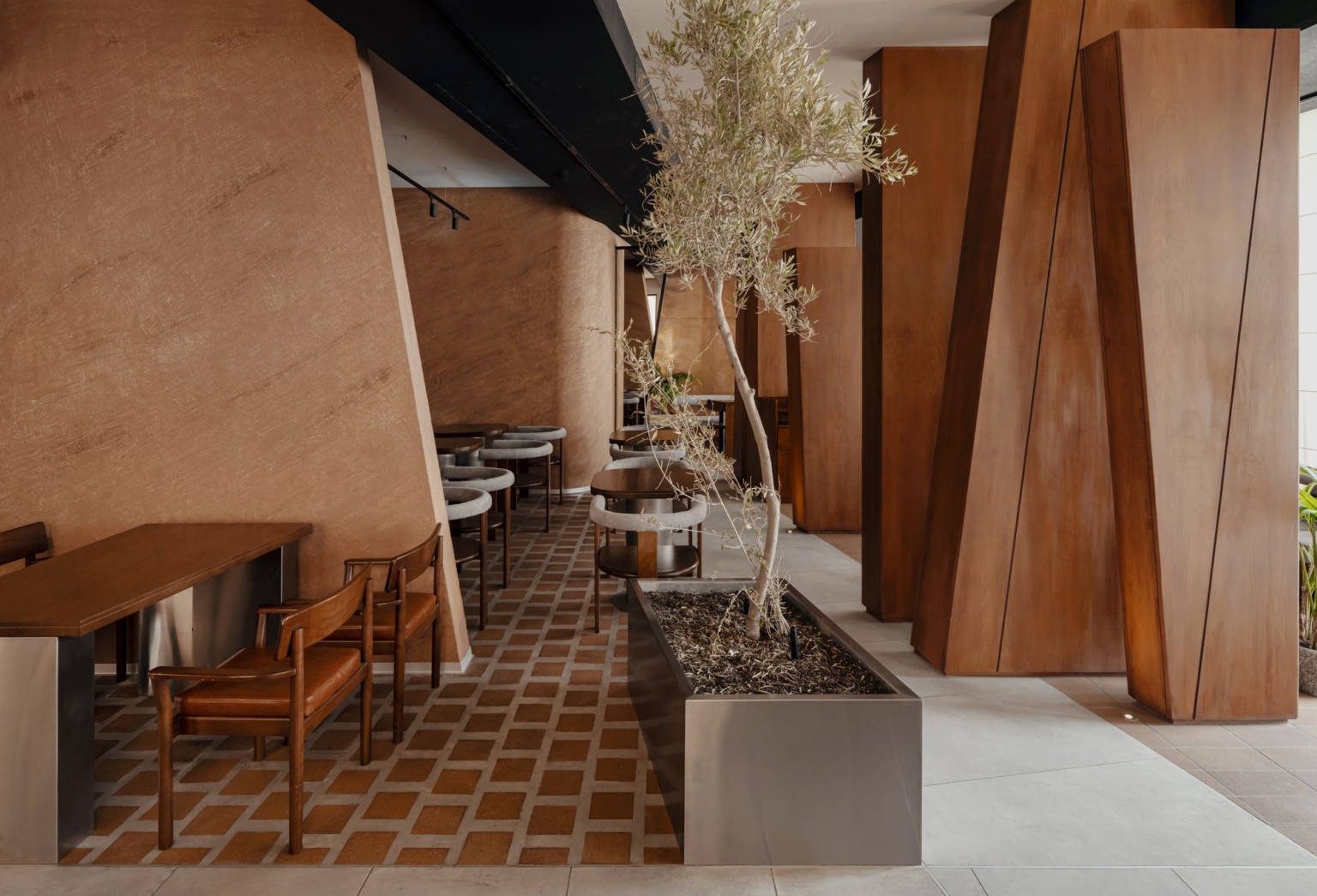 Olive tree growing between sculptural wooden columns